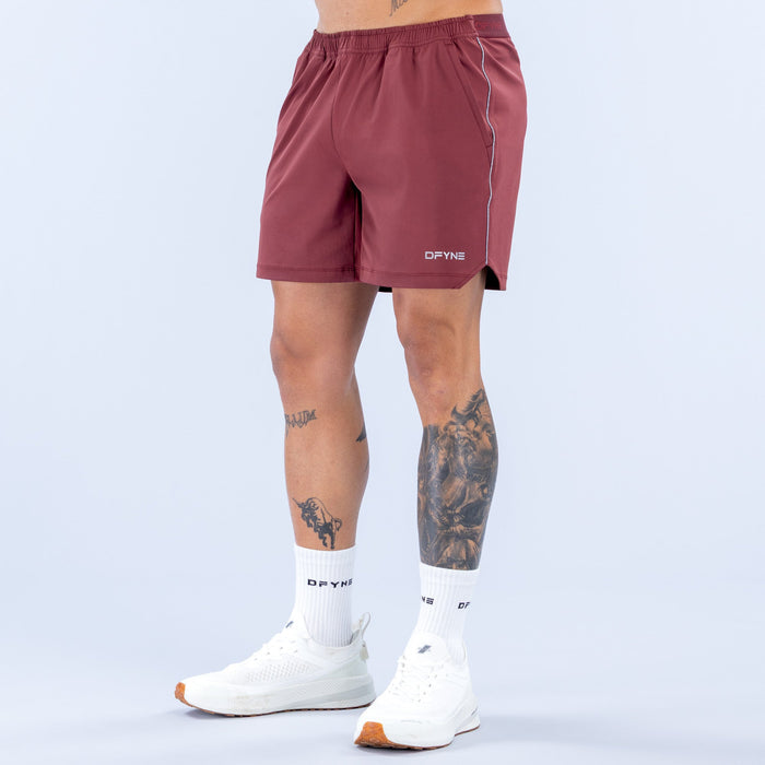 Maroon training shorts with elastic waistband and side logo patch