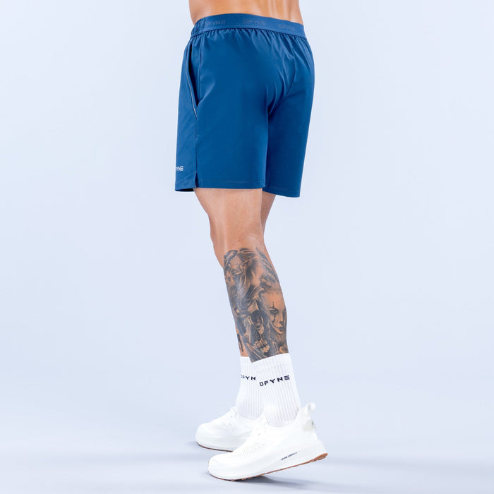 Men's blue training shorts, side view, elastic waistband and logo near hem, 6 in inseam