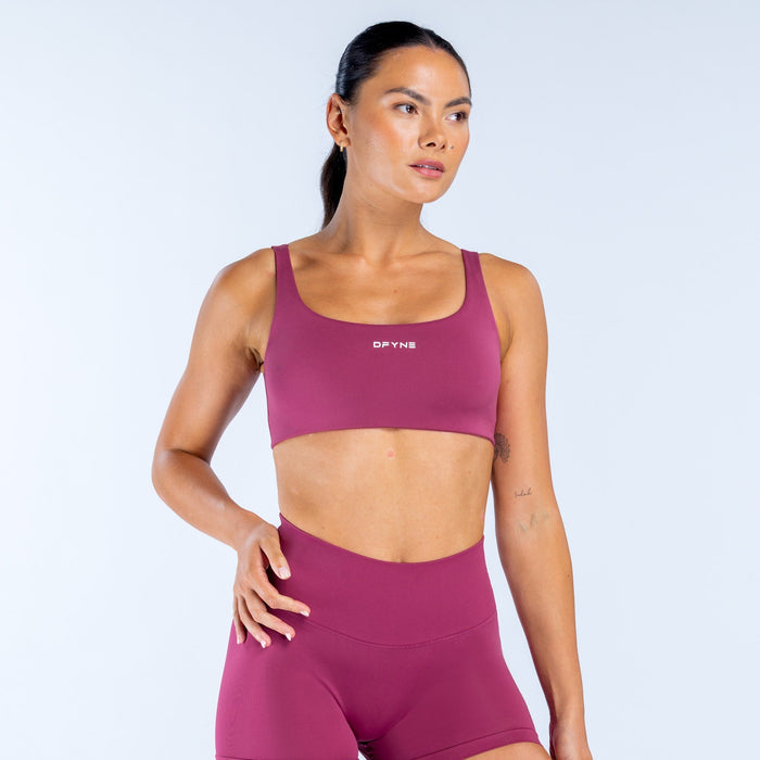 Magenta scoop front sports bra with logo badge at chest and smooth bonded seams