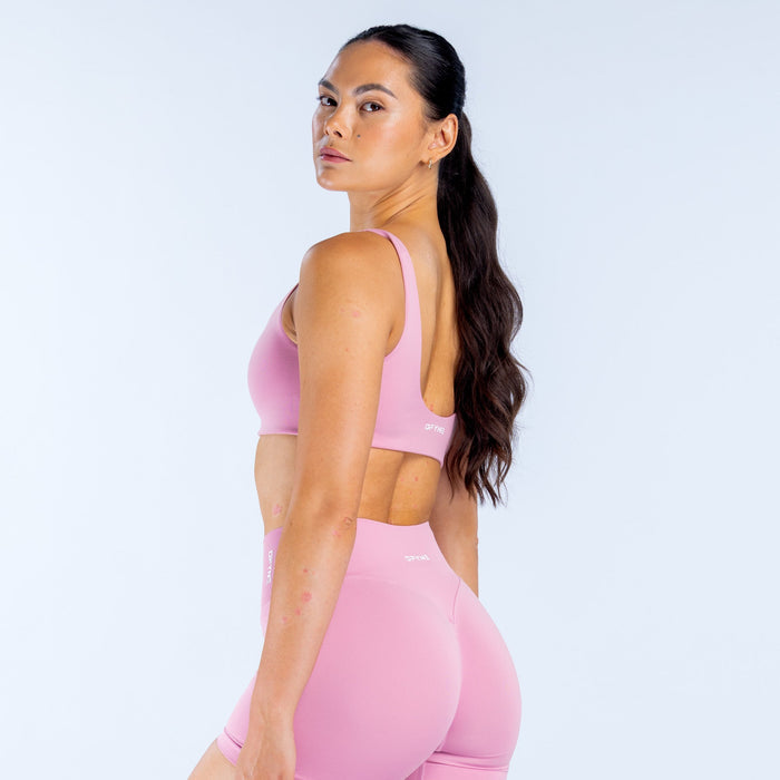 Pink scoop-back sports bra from the side, racerback straps visible