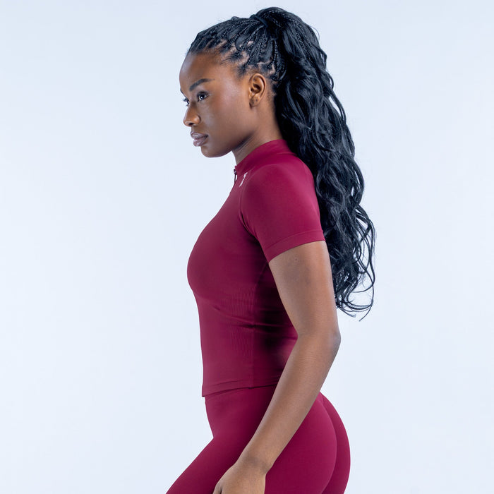 Burgundy short-sleeve zip-up athletic top, side view, fitted with front zipper