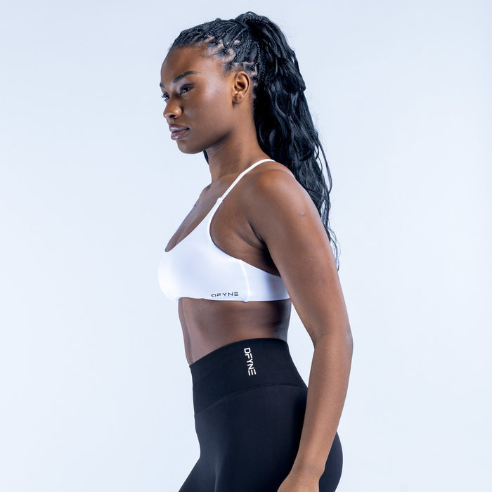 White twist-back sports bra shown from the side with back strap detail