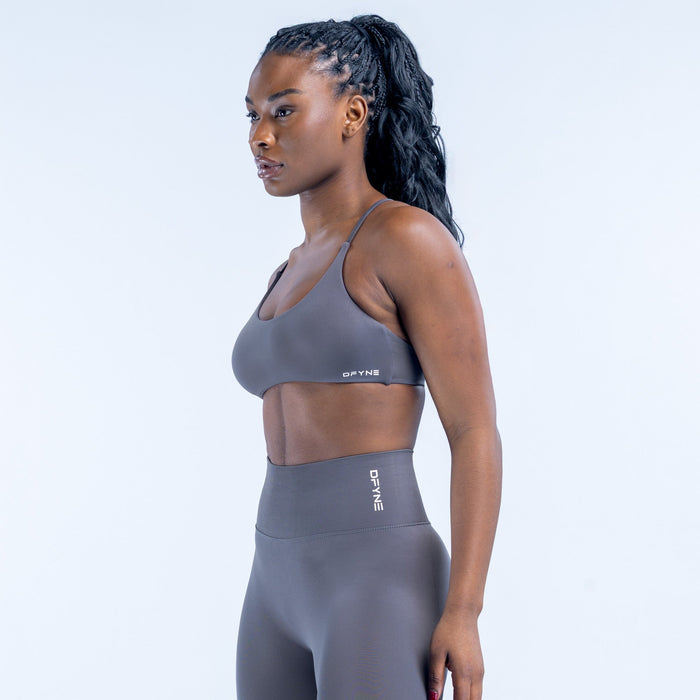 Dark gray sports bra with low scoop neckline and small side logo label