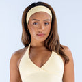 Light beige headband worn across forehead on model