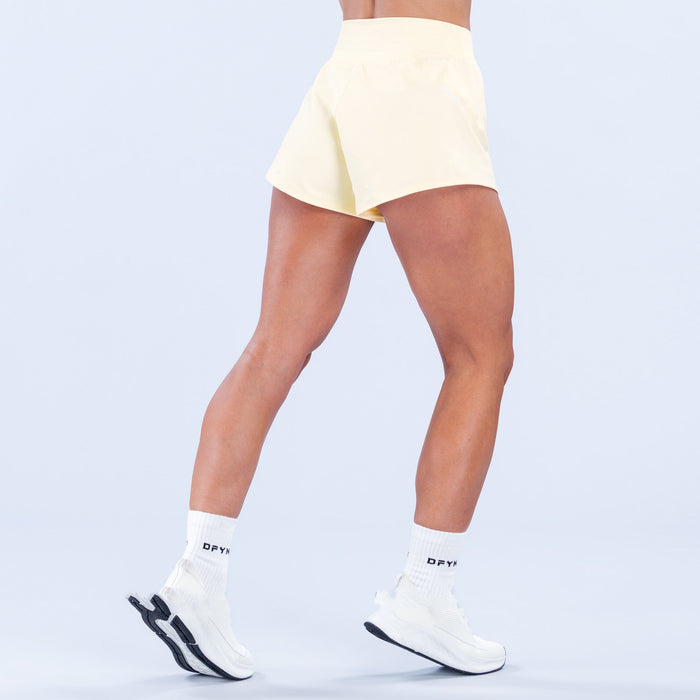 Light yellow training shorts with elastic waistband, back view, above-knee hem