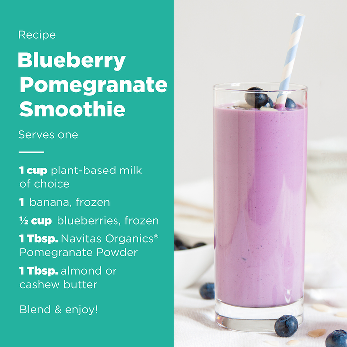 Recipe for a blueberry pomegranate smoothie with ingredients including Navitas Organics Pomegranate Powder listed next to a glass containing the smoothie, garnished with blueberries and a striped straw.