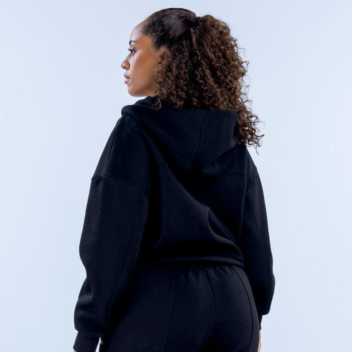 Black zip-front hoodie on model, rear view of hood and back shoulder shape