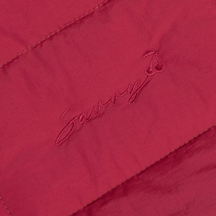 Red fabric patch with embroidered logo on quilted puffer bag.