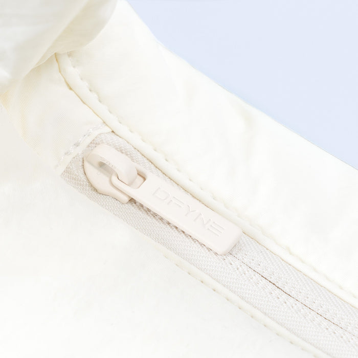 Sav puffer bag close-up of zipper and fabric trim on ivory quilted panel