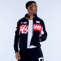 Black track jacket with red-and-white chest band, zip front, stand collar, logo patches