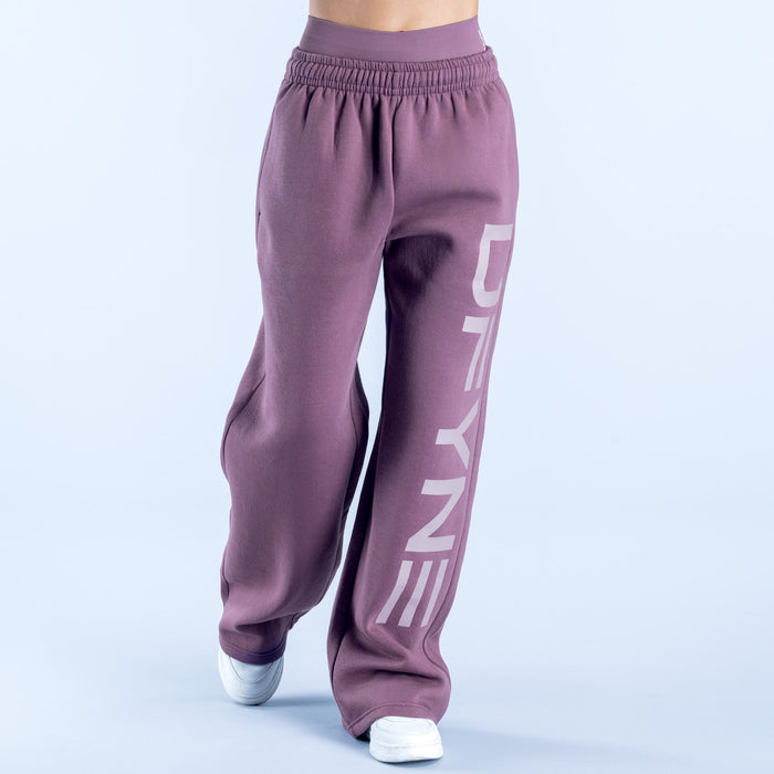 Purple wide-leg jogger pants with elastic waistband and large vertical logo stripe
