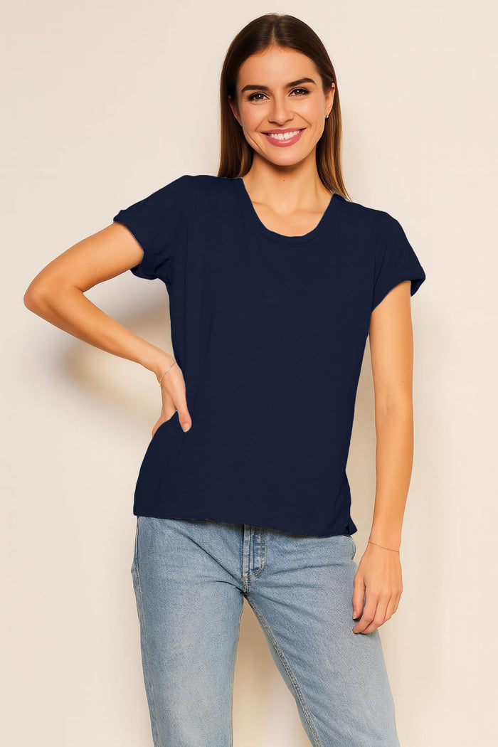 Woman wearing a black t-shirt and blue jeans against a plain background
