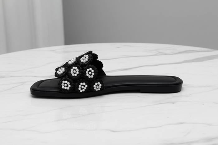 Tavo Black Pearl Flower Flat Slide Sandals – side profile view on white marble