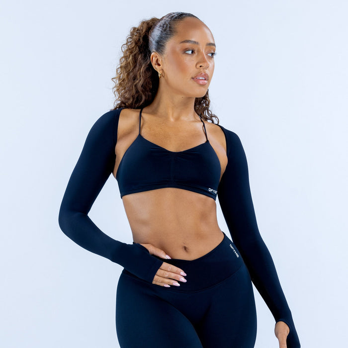 Navy long-sleeve shrug with thumbholes over a sports bra