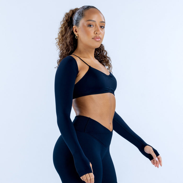Navy long-sleeve shrug with thumbholes, worn over a sports bra