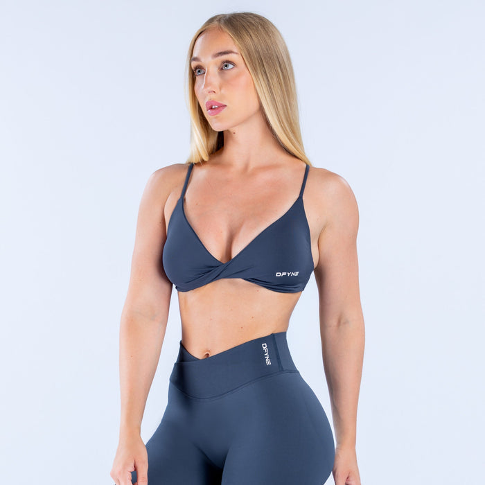Navy V-neck twist-front sports bra with thin straps and small logo patch
